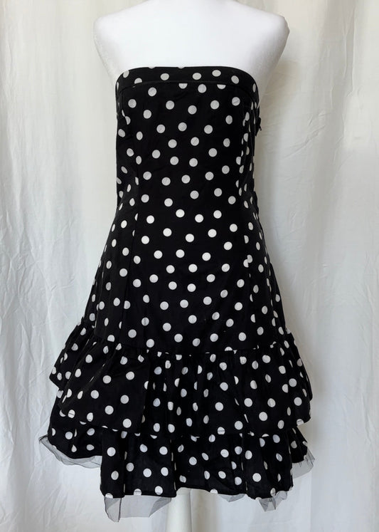 Black strapless dress with white polka dots on a mannequin against a white background