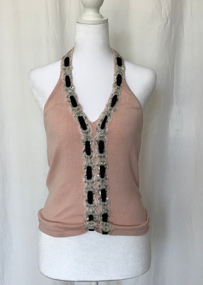 Beige sleeveless top with decorative black and silver trim on a mannequin against a white background
