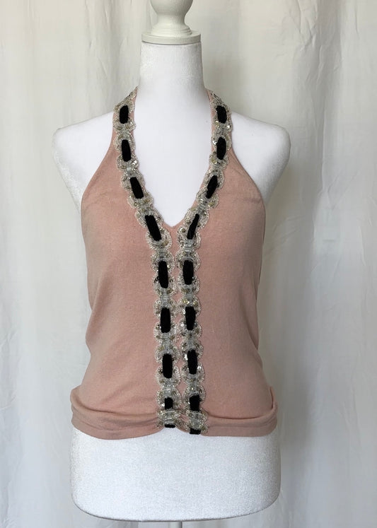 Beige sleeveless top with decorative black and silver trim on a mannequin against a white background