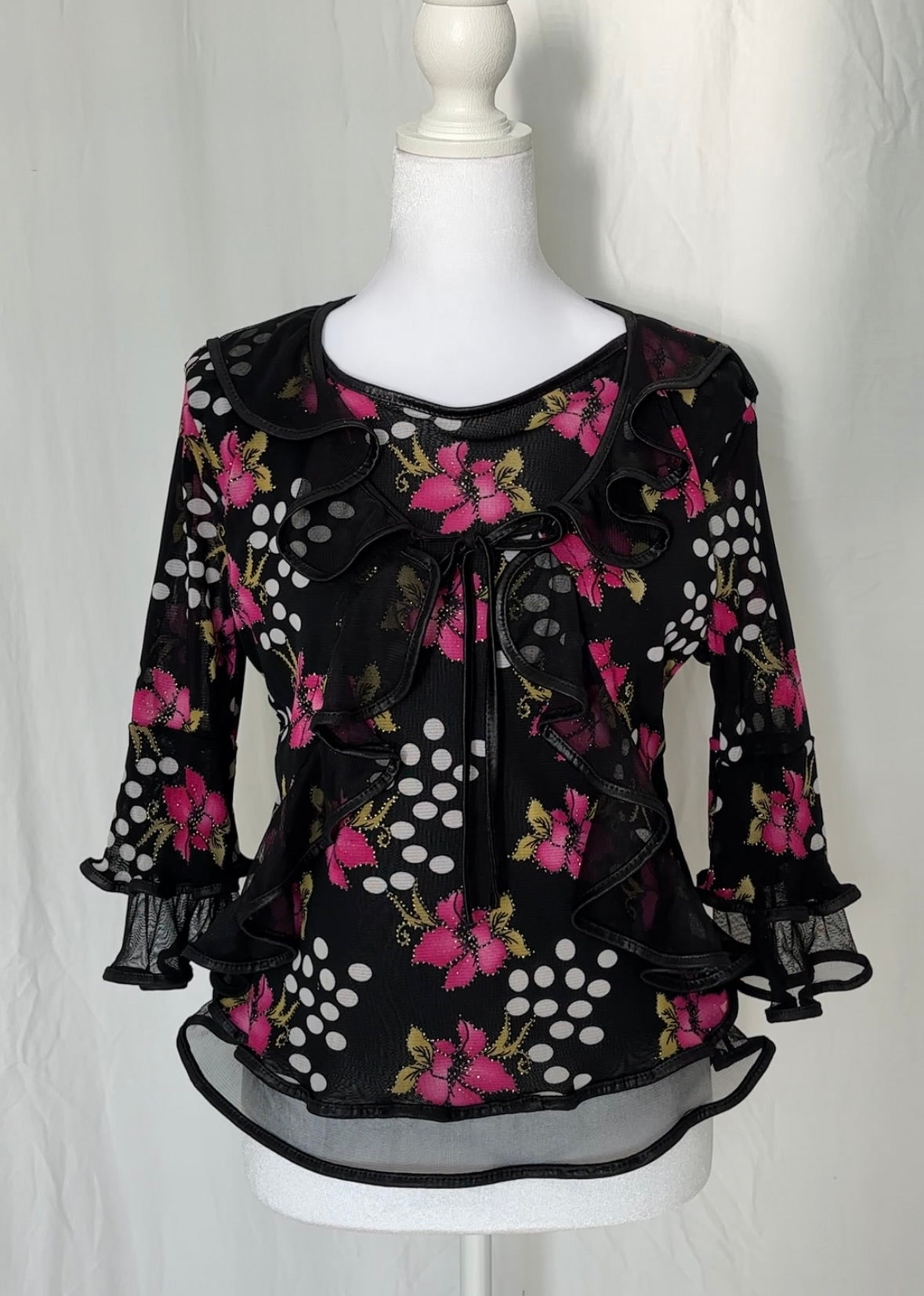Black floral blouse on a mannequin against a white background